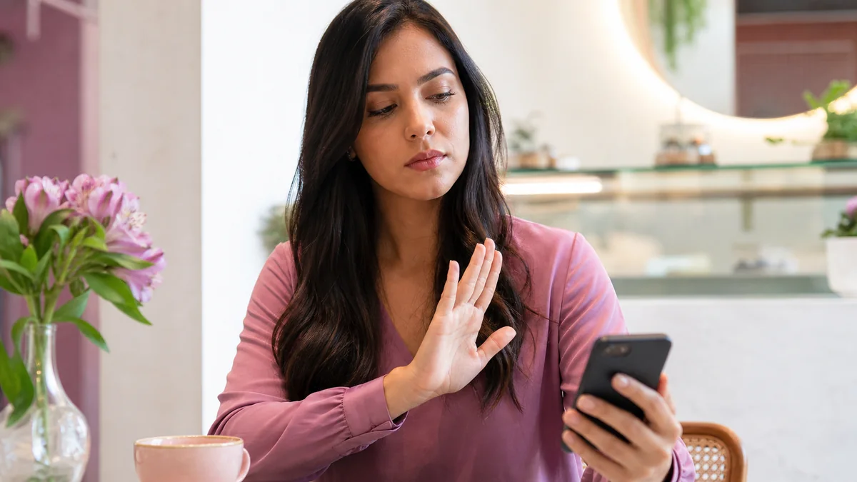 Mulher brasileira adulta reconhecendo uma mensagem suspeita no celular.